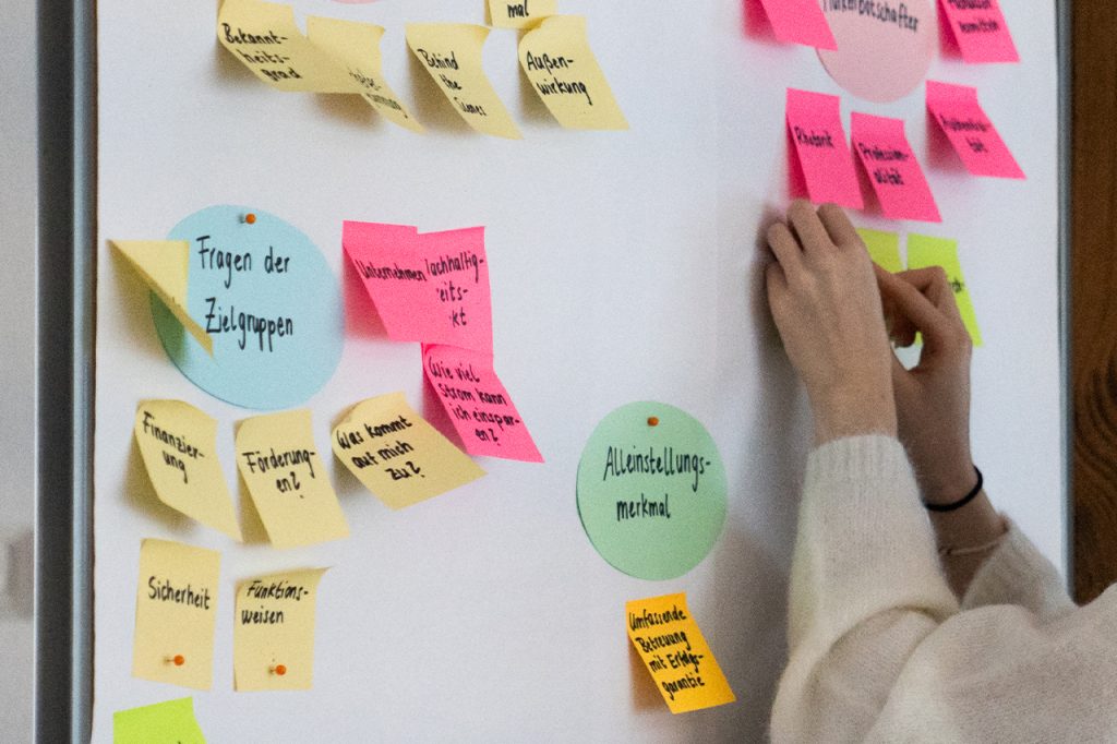 Person, die Post-It-Notizen an eine Tafel klebt